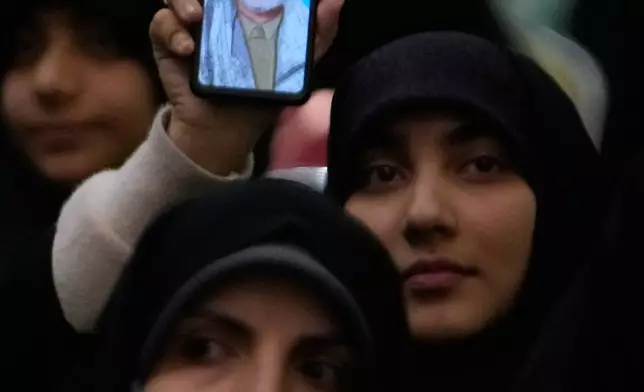 A woman shows a portrait of the late commander of Iran's Revolutionary Guard expeditionary Quds Force, Gen. Qassem Soleimani, who was killed in a U.S. drone attack in 2020 in Iraq, on her smartphone during a ceremony commemorating his death anniversary at the Imam Khomeini grand mosque in Tehran, Iran, Thursday, Jan. 1, 2026. (AP Photo/Vahid Salemi)