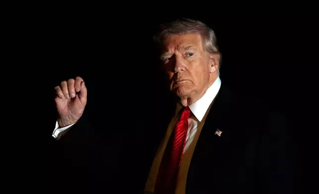 FILE - President Donald Trump is illuminated by a camera flash as he gestures while walking across the South Lawn of the White House, Nov. 2, 2025, in Washington, after returning from a trip to Florida. (AP Photo/Mark Schiefelbein, File)