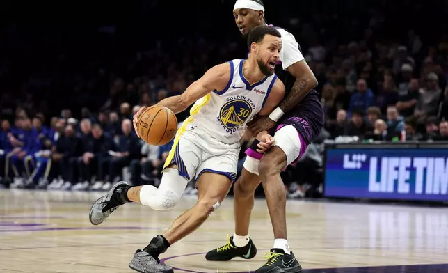 Golden State Warriors guard Stephen Curry (30) works around Minnesota Timberwolves forward Jaden McDaniels, top, during the first half of an NBA basketball game Sunday, Jan. 25, 2026, in Minneapolis. (AP Photo/Matt Krohn)