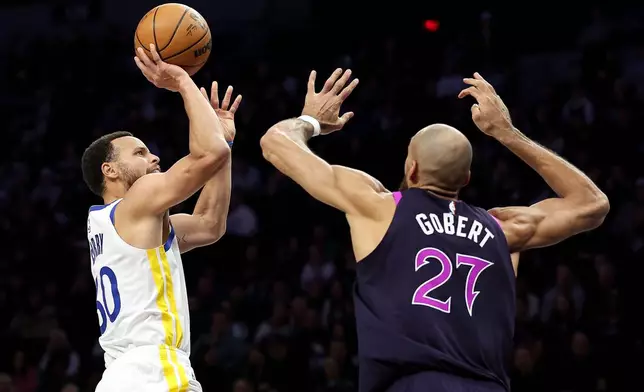 Golden State Warriors guard Stephen Curry, left, shoots over Minnesota Timberwolves center Rudy Gobert (27) during the first half of an NBA basketball game Sunday, Jan. 25, 2026, in Minneapolis. (AP Photo/Matt Krohn)