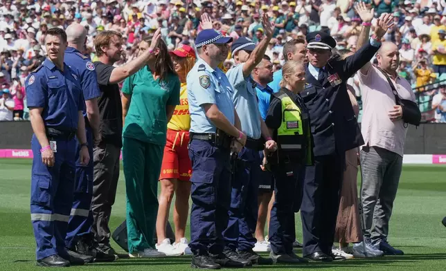 First responders and survivors from the Bondi Beach shooting wave from the field during a ceremony ahead play on day one of the fifth and final Ashes cricket test between England and Australia in Sydney, Sunday, Jan. 4, 2026. (AP Photo/Mark Baker)