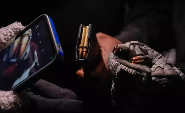 Protesters display two magazines of live ammunition found on the ground after federal immigration officers deployed tear gas and disrupted a demonstration outside the Bishop Whipple Federal Building, Monday, Jan. 12, 2026, in Minneapolis. (AP Photo/Jen Golbeck)