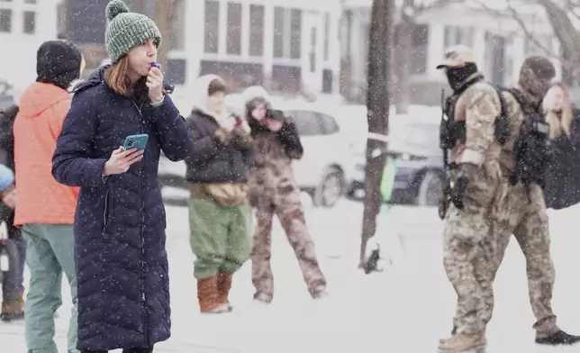 Observers look on as Federal agents stand outside a convenience store on Wednesday, Jan. 21, 2026, in Minneapolis. (AP Photo/Angelina Katsanis)