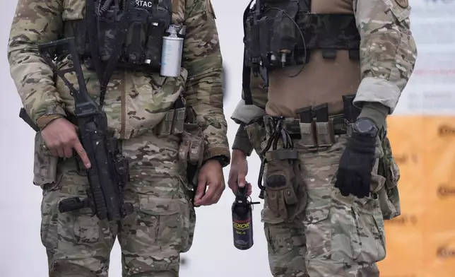 Federal agents stand outside a convenience store on Wednesday, Jan. 21, 2026, in Minneapolis. (AP Photo/Angelina Katsanis)
