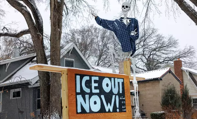 A human skeleton decoration dressed in a flannel shirt stands above a handmade sign reading "ICE OUT NOW!" outside a home in a residential neighborhood on Wednesday, Jan. 21, 2026, in Minneapolis. (Kerem Yücel/Minnesota Public Radio via AP)