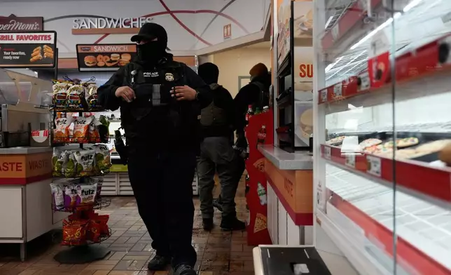 ICE agents make use of the facilities at a gas station, Monday, Jan. 19, 2026, in St. Paul, Minn. (AP Photo/Yuki Iwamura)