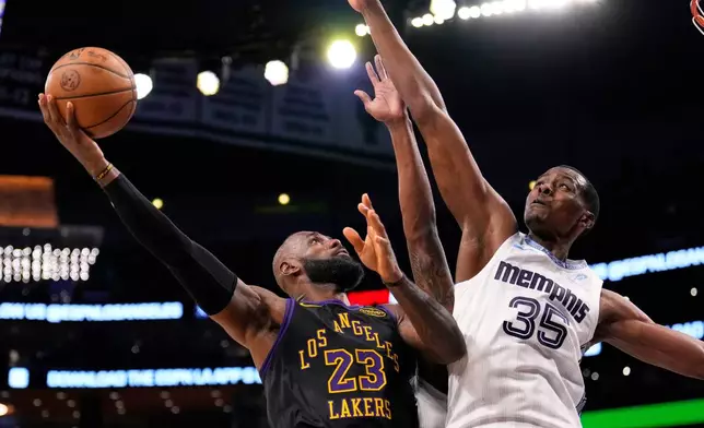 Los Angeles Lakers forward LeBron James, left, shoots as Memphis Grizzlies center Christian Koloko defends during the second half of an NBA basketball game Friday, Jan. 2, 2026, in Los Angeles. (AP Photo/Mark J. Terrill)