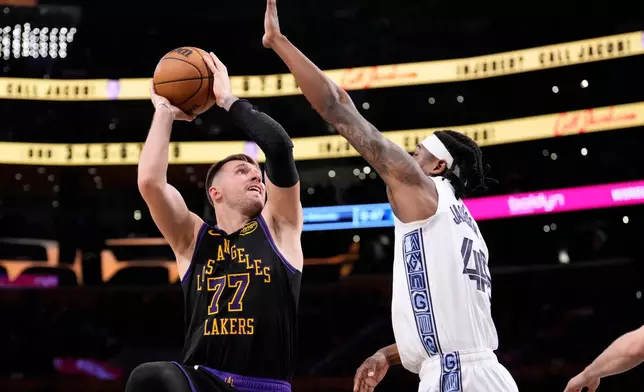 Los Angeles Lakers guard Luka Doncic, left, shoots as Memphis Grizzlies forward GG Jackson defends during the second half of an NBA basketball game Friday, Jan. 2, 2026, in Los Angeles. (AP Photo/Mark J. Terrill)