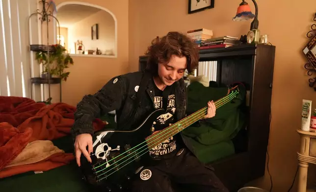 Kaden Rummler, who was injured after being hit with a projectile fired by a federal agent during a protest outside an immigration building in Santa Ana, Calif., plays the bass at home Wednesday, Jan. 14, 2026, in Southern California. (AP Photo/Damian Dovarganes)