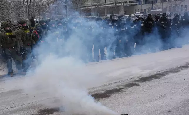 Federal immigration officers stand outside Bishop Henry Whipple Federal Building as tear gas is deployed Thursday, Jan. 15, 2026, in Minneapolis. (AP Photo/Adam Gray)
