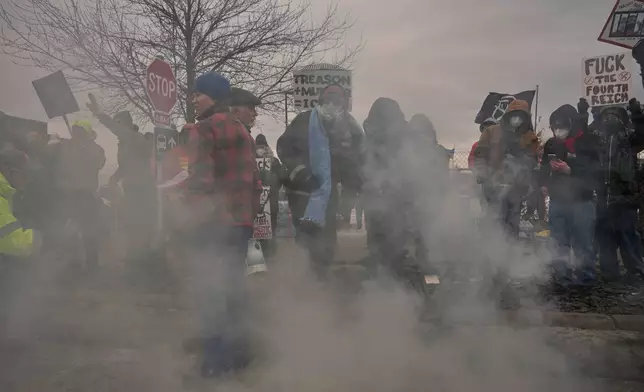 People cover tear gas deployed by federal immigration officers outside Bishop Henry Whipple Federal Building, Thursday, Jan. 15, 2026, in Minneapolis. (AP Photo/Adam Gray)