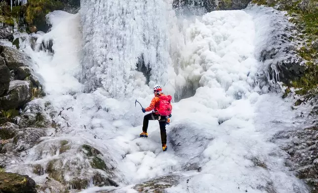 Lost Earth Adventures' instructor Mick Ellerton climbs a frozen waterfall in Gordale Scar near Malham Cove in the Yorkshire Dales National Park, as ice warnings are in place across the UK ahead of a storm which is set to bring heavy snow later in the week, on Wednesday Jan. 7, 2026. (Danny Lawson/PA via AP)