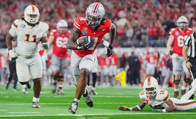 Ohio State wide receiver Jeremiah Smith, center, gets away from Miami defensive lineman David Blay Jr. (11) and defensive back Ja'Boree Antoine (16) to score a touchdown on a pass from quarterback Julian Sayin, not visible, during the second half of the Cotton Bowl College Football Playoff quarterfinal game Wednesday, Dec. 31, 2025, in Arlington, Texas. (AP Photo/Julio Cortez)
