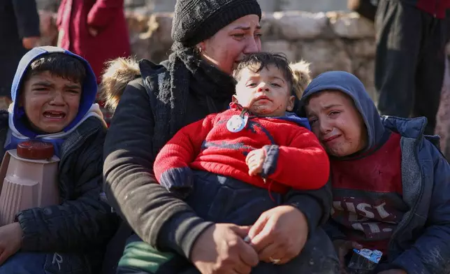 A woman and her children react with distress as civilians evacuate an area of the Sheikh Maqsoud neighborhood, where clashes between government forces and Kurdish fighters have been taking place in the northern city of Aleppo, Syria, Saturday, Jan. 10, 2026. (AP Photo/Ghaith Alsayed)