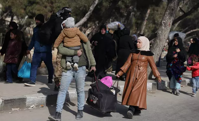 Residents carry their belongings as they are fleeing from Sheikh Maqsoud and Achrafieh neighborhoods after clashes broke out on Tuesday between Syrian government forces and Kurdish fighters in a contested area of the northern city of Aleppo, Syria, Wednesday, Jan. 7, 2026. (AP Photo/Omar Albam)