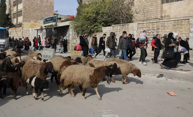 Residents carry their belongings, as they are fleeing from Sheikh Maqsoud and Achrafieh neighborhoods after clashes broke out on Tuesday between Syrian government forces and Kurdish fighters in a contested area of the northern city of Aleppo, Syria, Wednesday, Jan. 7, 2026. (AP Photo/Omar Albam)