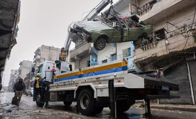 Civil Defense remove a damaged car in the predominantly Kurdish Sheikh Maqsoud neighborhood where clashes broke out Tuesday Jan. 6 between government forces and the Kurdish-led Syrian Democratic Forces in the northern city of Aleppo, Syria, Monday, Jan. 12, 2026. (AP Photo/Omar Albam)