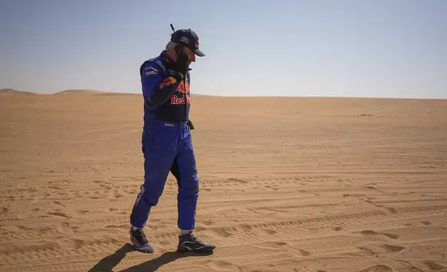 Driver Carlos Sainz gives a phone call at the end of the ninth stage of the Dakar Rally between Wadi Ad Dawasir and Bisha, Saudi Arabia, Tuesday, Jan.13, 2026. (AP Photo/Thibault Camus)