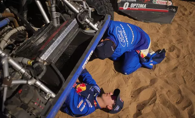 Driver Mattias Ekstrom and co-driver Emil Bergkvist check their car at the end of the ninth stage of the Dakar Rally between Wadi Ad Dawasir and Bisha, Saudi Arabia, Tuesday, Jan.13, 2026. (AP Photo/Thibault Camus)