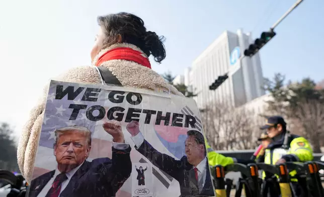 A supporter of former South Korean President Yoon Suk Yeol waits for a bus carrying former South Korean President Yoon Suk Yeol outside Seoul Central District Court, in Seoul, South Korea, Friday, Jan. 16, 2026. (AP Photo/Lee Jin-man)