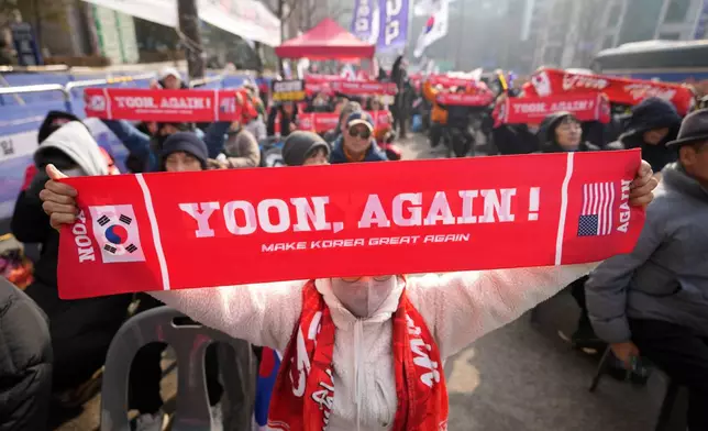 Supporters of former South Korean President Yoon Suk Yeol hold signs outside Seoul Central District Court, in Seoul, South Korea, Friday, Jan. 16, 2026. (AP Photo/Lee Jin-man)