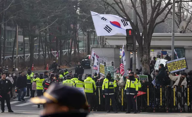 Supporters of former South Korean President Yoon Suk Yeol hold signs and flags outside Seoul Central District Court, in Seoul, South Korea, Friday, Jan. 16, 2026. (AP Photo/Lee Jin-man)