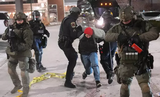 Law enforcement officers detain a demonstrator during a protest outside SpringHill Suites and Residence Inn by Marriott hotels on Monday, Jan. 26, 2026, in Maple Grove, Minn. (AP Photo/Adam Gray)