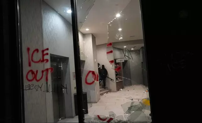 A smashed window is seen at a hotel during a noise demonstration protest in response to federal immigration enforcement operations in the city Sunday, Jan. 25, 2026, in Minneapolis. (AP Photo/Adam Gray)