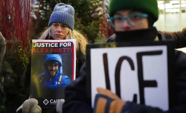 Demonstrator holds signs during a protest outside the office of Sen. Amy Klobuchar, D-Minn., on Monday, Jan. 26, 2026, in Minneapolis, after Alex Pretti was fatally shot by a U.S. Border Patrol officer over the weekend. (AP Photo/Adam Gray)