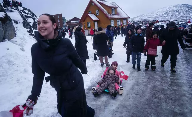 A woman pulls her children on a sled during a protest against Trump's policy towards Greenland in front of the US consulate in Nuuk, Greenland, Saturday, Jan. 17, 2026. (AP Photo/Evgeniy Maloletka)