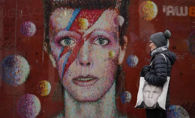 A fan looks at a mural on the 10th anniversary of the death of David Bowie in London, Saturday, Jan. 10, 2026. (AP Photo/Kin Cheung)