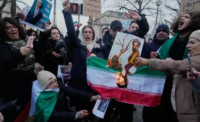 Protesters burn the Iranian national flag during a rally in support of the nationwide mass demonstrations in Iran against the government in Paris, Sunday, Jan. 11, 2026. (AP Photo/Michel Euler)
