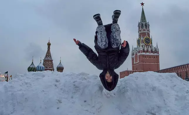 A girl shows off her skills atop of a pile of snow on Red Square after heavy snowfall in Moscow, on Saturday, Jan. 10, 2026, backdropped by the St. Basil's Cathedral. (AP Photo/Alexander Zemlianichenko)