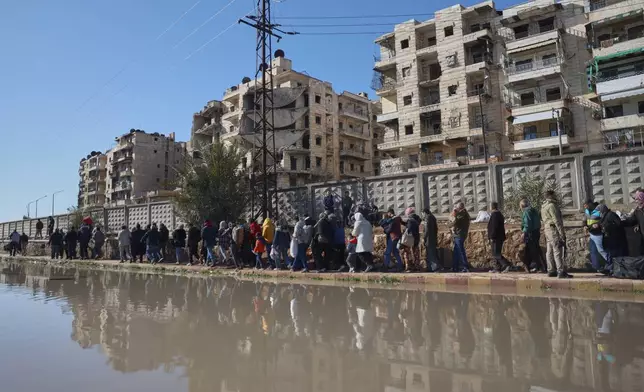 Civilians evacuate an area of the Sheikh Maqsoud neighborhood, where clashes between government forces and Kurdish fighters have been taking place in the northern city of Aleppo, Syria, Saturday, Jan. 10, 2026. (AP Photo/Omar Albam)
