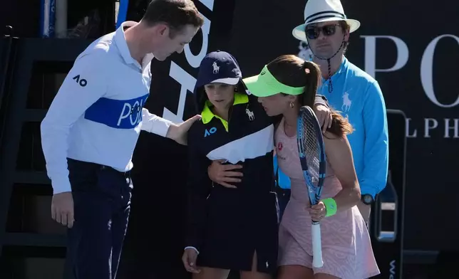 Zeynep Sonmez of Turkey and umpire Chase Urban help a ball kid who fainted, from the court during her first round match against Ekaterina Alexandrova of Russia at the Australian Open tennis championship in Melbourne, Australia, Sunday, Jan. 18, 2026. (AP Photo/Asanka Brendon Ratnayake)