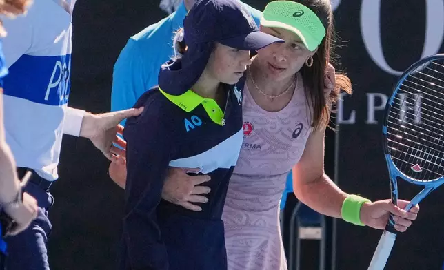 Zeynep Sonmez of Turkey and umpire Chase Urban help a ball kid who fainted from the court during her first round match against Ekaterina Alexandrova of Russia at the Australian Open tennis championship in Melbourne, Australia, Sunday, Jan. 18, 2026. (AP Photo/Asanka Brendon Ratnayake)