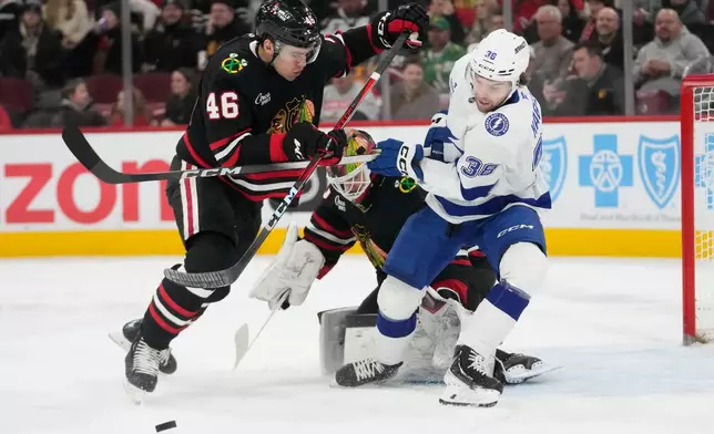 Chicago Blackhawks defenseman Louis Crevier (46) and Tampa Bay Lightning left wing Brandon Hagel (38) fight for control of the puck in front of the net during the first period of an NHL hockey game Friday, Jan. 23, 2026, in Chicago. (AP Photo/Erin Hooley)
