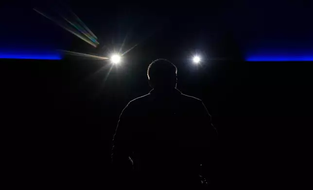Theater technician Cody Gerken is rimmed by projector light as he introduces the "Ohio: Wild at Heart" film that features the state's top-rated park system to highlight wildlife conservation efforts and the restorative power of outdoor recreation at the Robert D. Lindner Family OMNIMAX Theater at the Cincinnati Union Terminal, Tuesday, Dec. 30, 2025, in Cincinnati. (AP Photo/Carolyn Kaster)