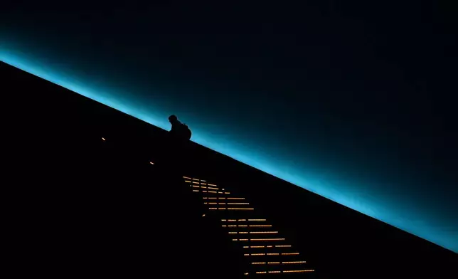 A patron climbs to their seat before a viewing of "Ohio: Wild at Heart" film that features the state's top-rated park system to highlight wildlife conservation efforts and the restorative power of outdoor recreation at the Robert D. Lindner Family OMNIMAX Theater at the Cincinnati Union Terminal, Tuesday, Dec. 30, 2025, in Cincinnati. (AP Photo/Carolyn Kaster)