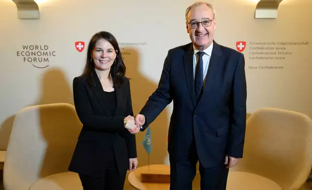 Swiss Federal President Guy Parmelin, right, shakes hands with United Nations' 80th General Assembly President and former German foreign minister Annalena Baerbock, left, prior to a bilateral meeting on the sideline of the 56th annual meeting of the World Economic Forum in Davos, Switzerland, Monday, Jan. 19, 2026. (Laurent Gillieron/Keystone via AP)