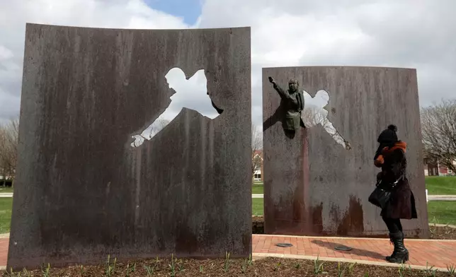FILE - A visitor pauses as she visits the memorial "Landmark for Peace" commemorating the site where Robert Kennedy delivered his immortal words on the night of Martin Luther King Jr's assassination in Indianapolis, Wednesday, April 4, 2018. The park where Kennedy called for peace and unity just hours after the assassination of King is being designated a National Historic Site. (AP Photo/Michael Conroy, File)