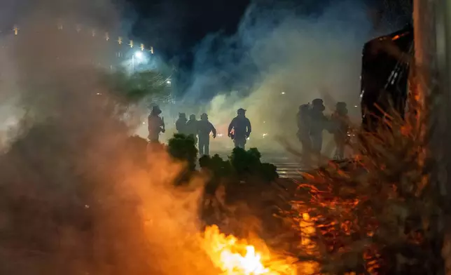 Federal immigration officers are seen outside Bishop Whipple Federal Building after tear gas was deployed Monday, Jan. 12, 2026, in Minneapolis. (AP Photo/Jen Golbeck)