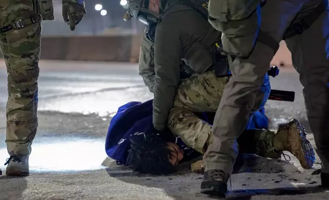 Federal immigration officers detain a demonstrator outside Bishop Whipple Federal Building after tear gas was deployed Monday, Jan. 12, 2026, in Minneapolis. (AP Photo/Jen Golbeck)