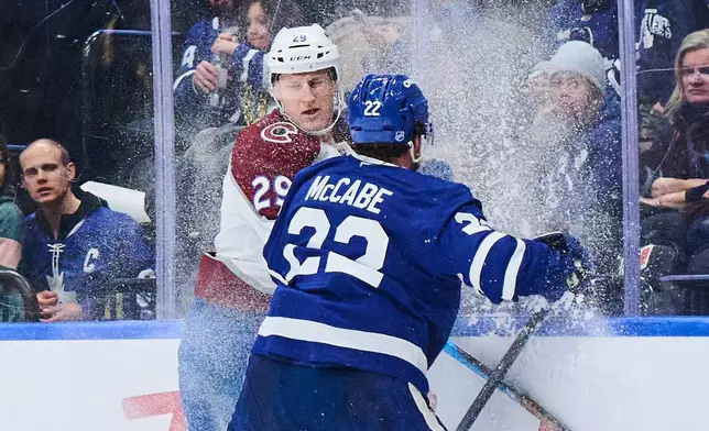 Colorado Avalanche's Nathan MacKinnon (29) and Toronto Maple Leafs' Jake McCabe (22) collide during first period NHL hockey action in Toronto, on Sunday, Jan. 25, 2026. (Sammy Kogan/The Canadian Press via AP)
