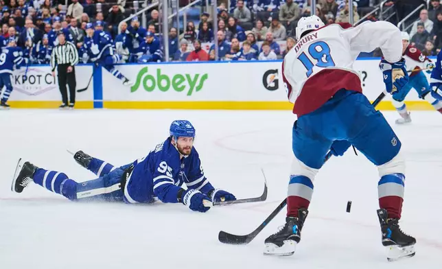 Toronto Maple Leafs' Oliver Ekman-Larsson (95) dives for the puck as Colorado Avalanche's Jack Drury (18) lines up a shot during first period NHL hockey action in Toronto, on Sunday, Jan. 25, 2026. (Sammy Kogan/The Canadian Press via AP)