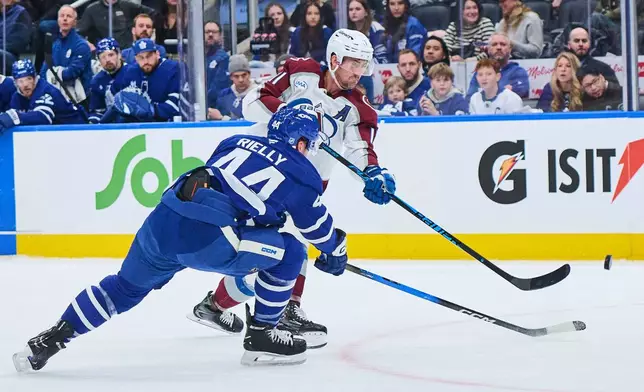 Colorado Avalanche's Brock Nelson (11) shoots past Toronto Maple Leafs' Morgan Rielly (44) during the first period of an NHL hockey game in Toronto, on Sunday, Jan. 25, 2026. (Sammy Kogan/The Canadian Press via AP)
