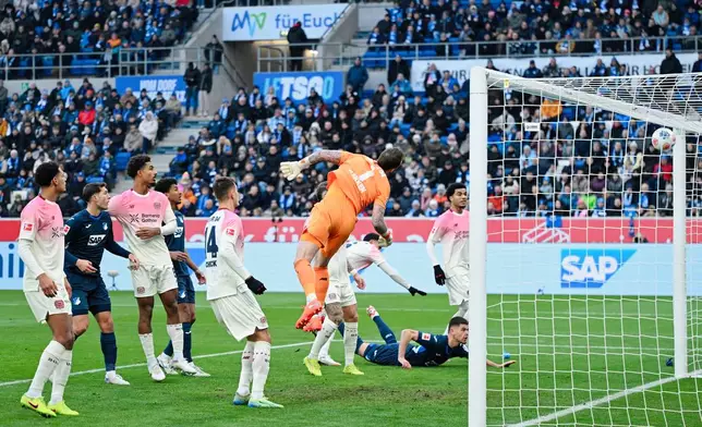 Leverkusen's goalkeeper Mark Flekken, centre, misses the opening goal by Hoffenheim's Wouter Burger during the German Bundesliga soccer match between TSG 1899 Hoffenheim and Bayer Leverkusen in Sinsheim, Germany, Saturday, Jan. 17, 2026. (Uwe Anspach/dpa via AP)