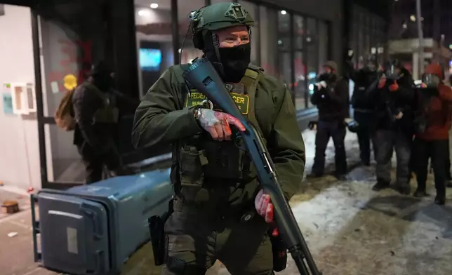 A federal agent stands guard near a hotel during a noise demonstration protest in response to federal immigration enforcement operations in the city Sunday, Jan. 25, 2026, in Minneapolis. (AP Photo/Adam Gray)
