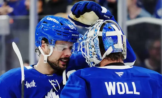 Toronto Maple Leafs' Auston Matthews, left, and goaltender Joseph Woll, right, celebrate after defeating the Vancouver Canucks in NHL hockey game action in Toronto, Saturday, Jan. 10, 2026. (Frank Gunn/The Canadian Press via AP)