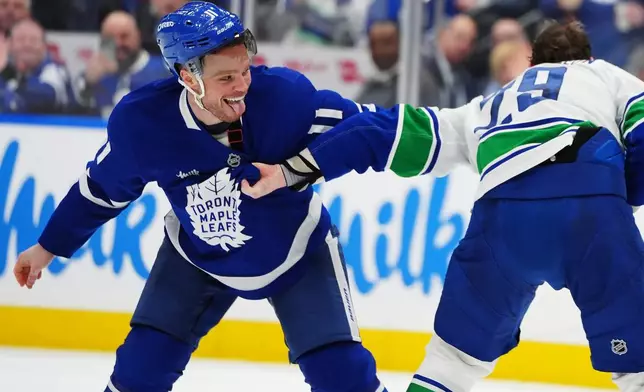 Toronto Maple Leafs' Max Domi, left, and Vancouver Canucks' Marcus Pettersson, right, fight during second-period NHL hockey game action in Toronto, Saturday, Jan. 10, 2026. (Frank Gunn/The Canadian Press via AP)